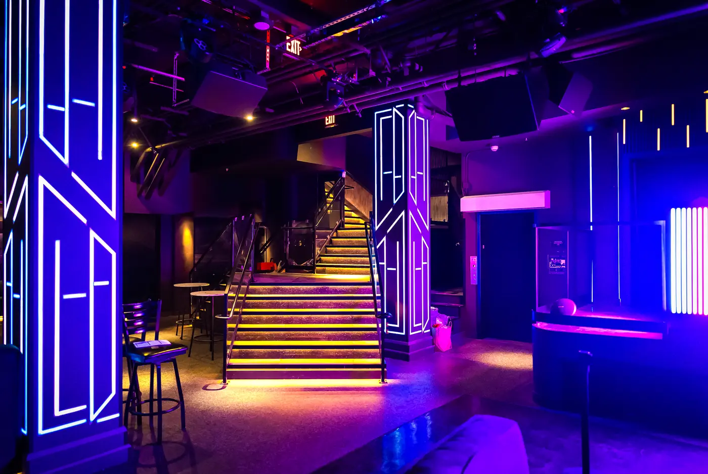 Terraced VIP banquettes under purple and cyan lighting at West 8